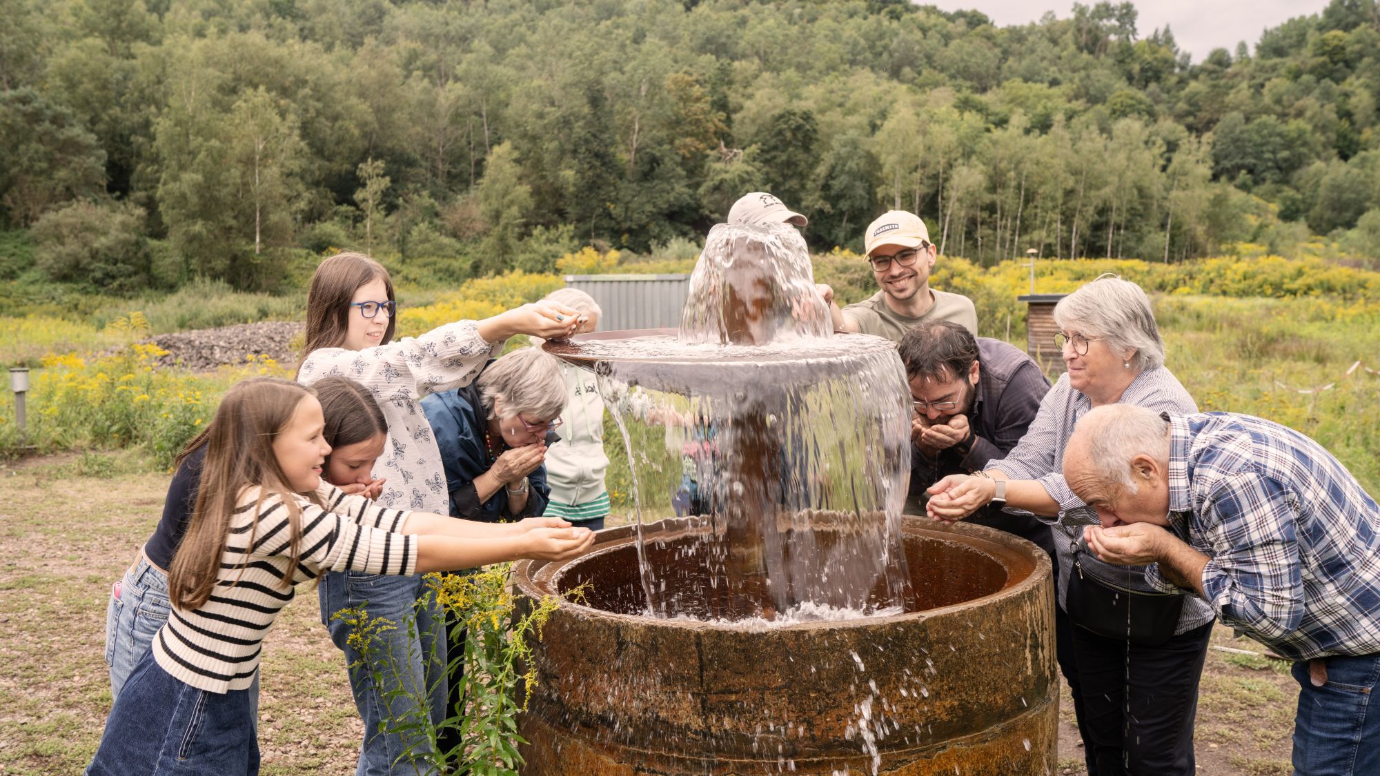 Besucher beim Wasser probieren am Brunnen